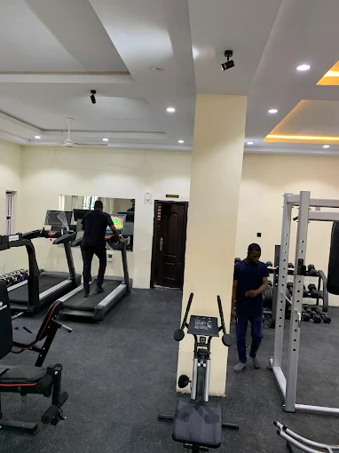 Spacious gym with treadmills and strength training under yellow lighting